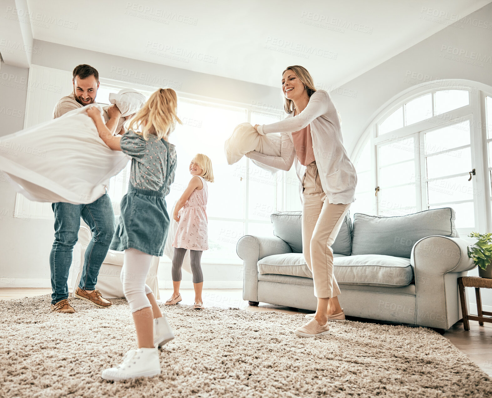 Buy stock photo Happy family, pillow fight and playing in living room together for fun holiday, weekend or bonding at home. Mother, father and children smile with cushion game, play or free time for summer break