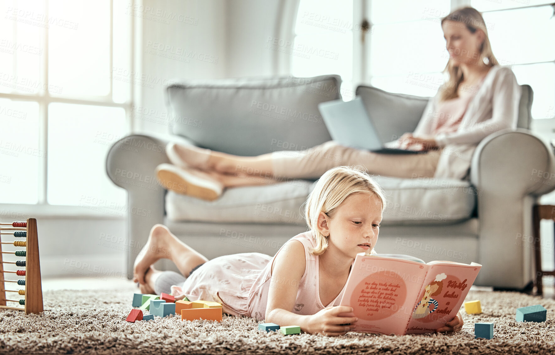 Buy stock photo Child, floor and reading book for learning, language development and mother work from home in living room. Girl or kid with English story, education and relax on carpet with mom or family on sofa