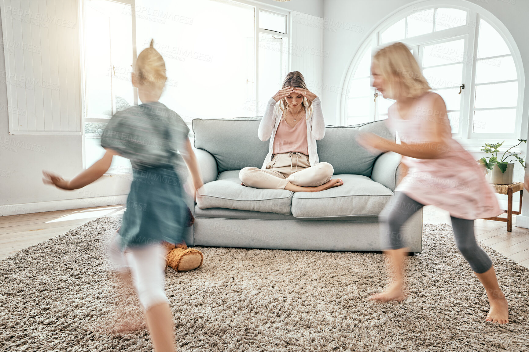 Buy stock photo Mother, children and running in living room chaos with headache in stress on sofa at crazy or busy home. Frustrated single parent in burnout with ADHD or hyperactive kids or siblings playing in house