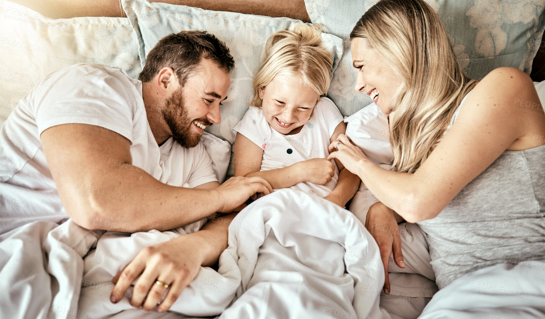 Buy stock photo Bed, top view and happy family bond with tickle, games and laughing in their home together. Bedroom, fun and above parents with girl child in a house with care, support and love, security or playing