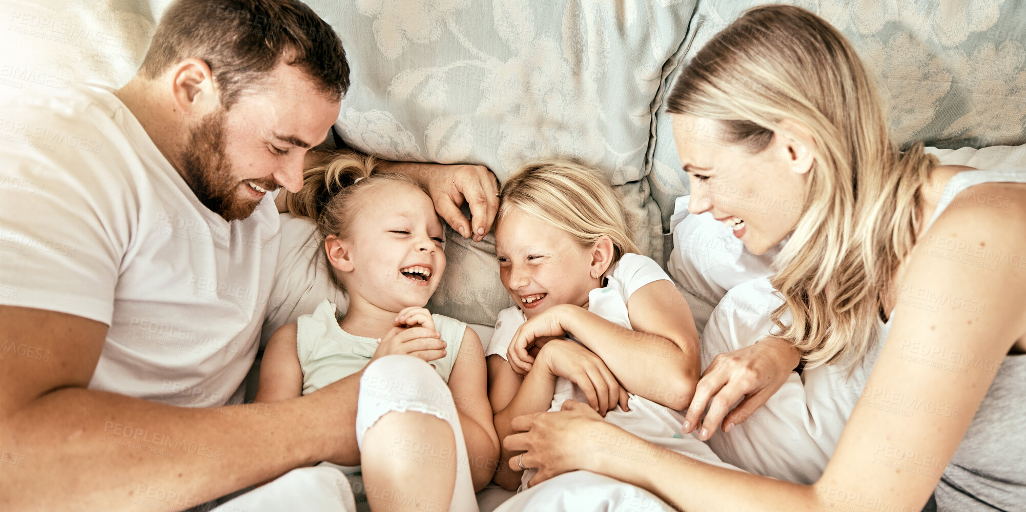 Buy stock photo Love, top view and happy family waking up laughing, playing and bond with tickle games in their home. Bedroom, fun and above children playing with parents in a house with care, support and security 