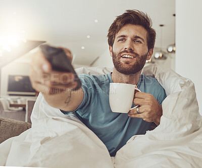 Buy stock photo Coffee, relax and a man in a blanket watching tv on a sofa in the living room of his home for entertainment streaming. Movie, television or subscription with a happy young person using a remote