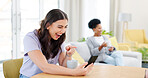 Phone, video call and young woman in the living room laughing in conversation at home. Smile, technology and happy female person on virtual discussion with cellphone by table in modern apartment.