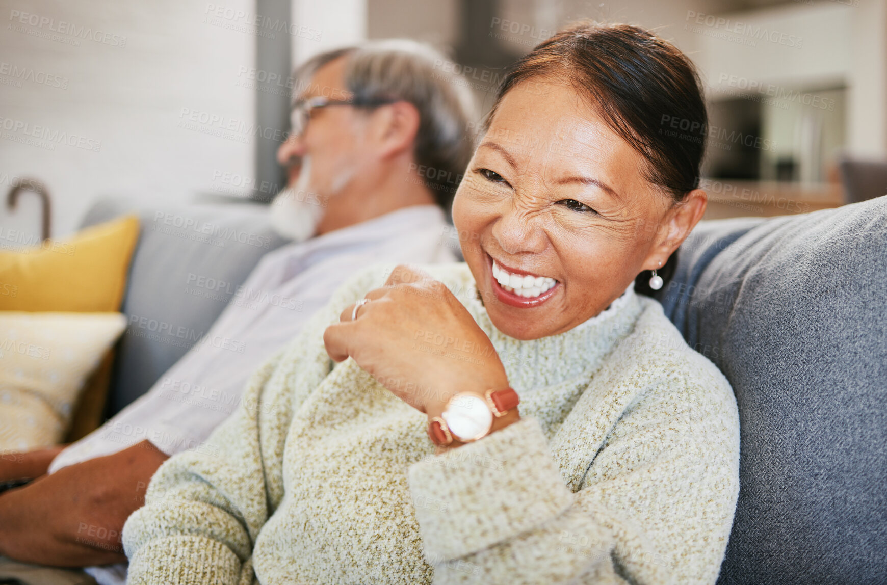 Buy stock photo Mature, woman and laugh on sofa with smile in lounge for joke on holiday, vacation or retirement. Face, elderly couple or asian person for funny, goofy or silly talk and relax with husband in home