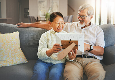 Buy stock photo Elderly couple, happy and together with memory or photograph on sofa with smile in living room. Senior man, woman and married with embrace by sit, bond and love in relationship for vacation, holiday