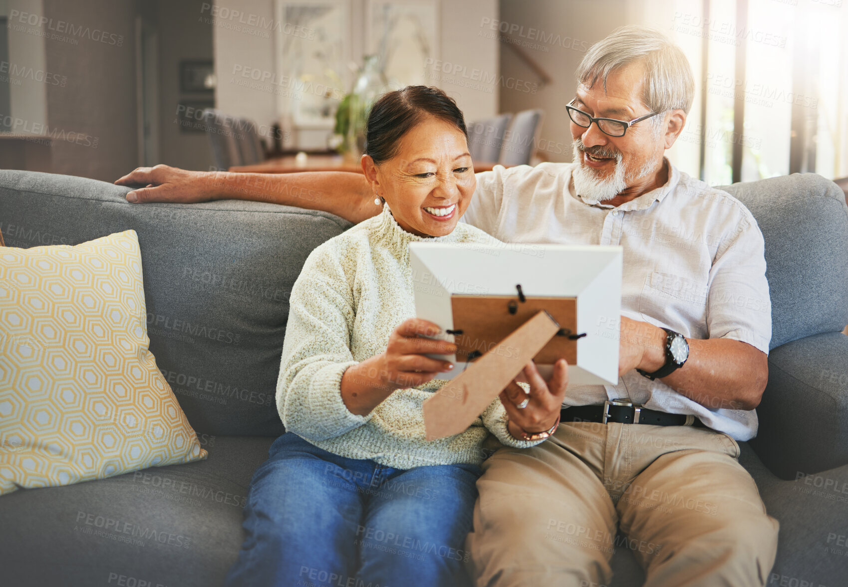 Buy stock photo Elderly couple, happy and together with memory or photograph on sofa with smile in living room. Senior man, woman and married with embrace by sit, bond and love in relationship for vacation, holiday