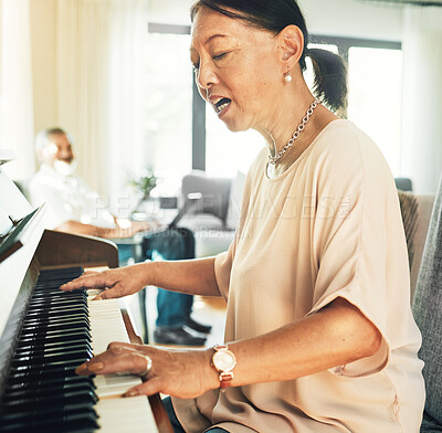 Buy stock photo Singing, piano and senior woman playing for music with husband in living room for bonding and entertainment. Instrument, practice and elderly Asian man and woman in retirement with keyboard at home.