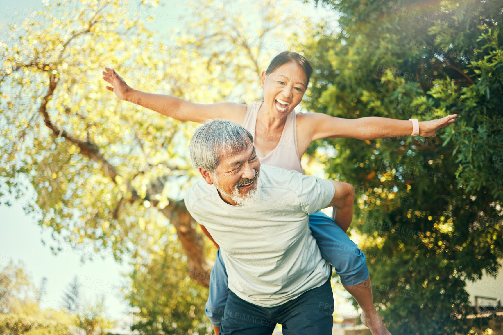 Buy stock photo Couple, smile and piggyback in nature for fun, excited and playful in freedom, energy and joy. Happy elderly asian people, airplane and flying in summer, laugh and support for crazy in retirement