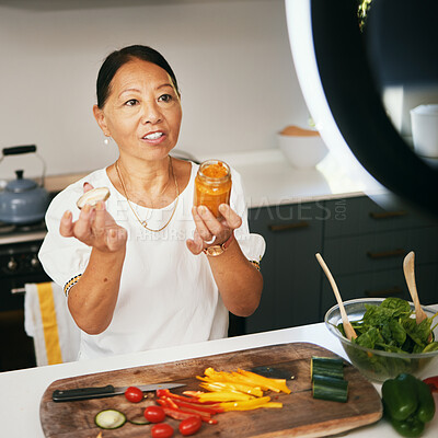 Buy stock photo Asian woman, vegetables and live streaming for cooking with bottle, healthy food and blog on social media in kitchen. Chef, mature influencer and content creation, class and broadcast online tutorial