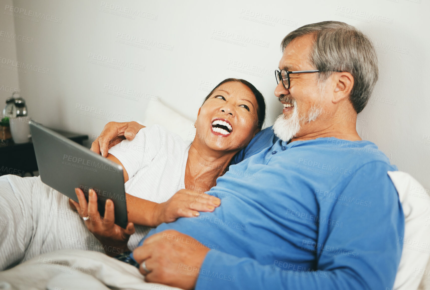 Buy stock photo Tablet, mature or happy couple in bed for movie watching on website subscription via internet connection. Meme, home or mature woman laughing at comedy with an Asian man streaming film on tech online