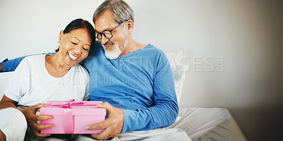 Buy stock photo Happy couple in bed, senior or hug for gift for anniversary, care or love in home, house or retirement. Giving, Asian man or excited mature woman with birthday present box for romance in bedroom