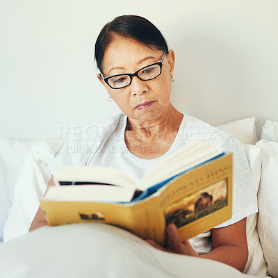 Buy stock photo Mature woman reading books in bedroom for story, fiction novel and knowledge at home. Serious asian person, glasses and comfortable in bed with literature for rest, hobby and relax to enjoy break 