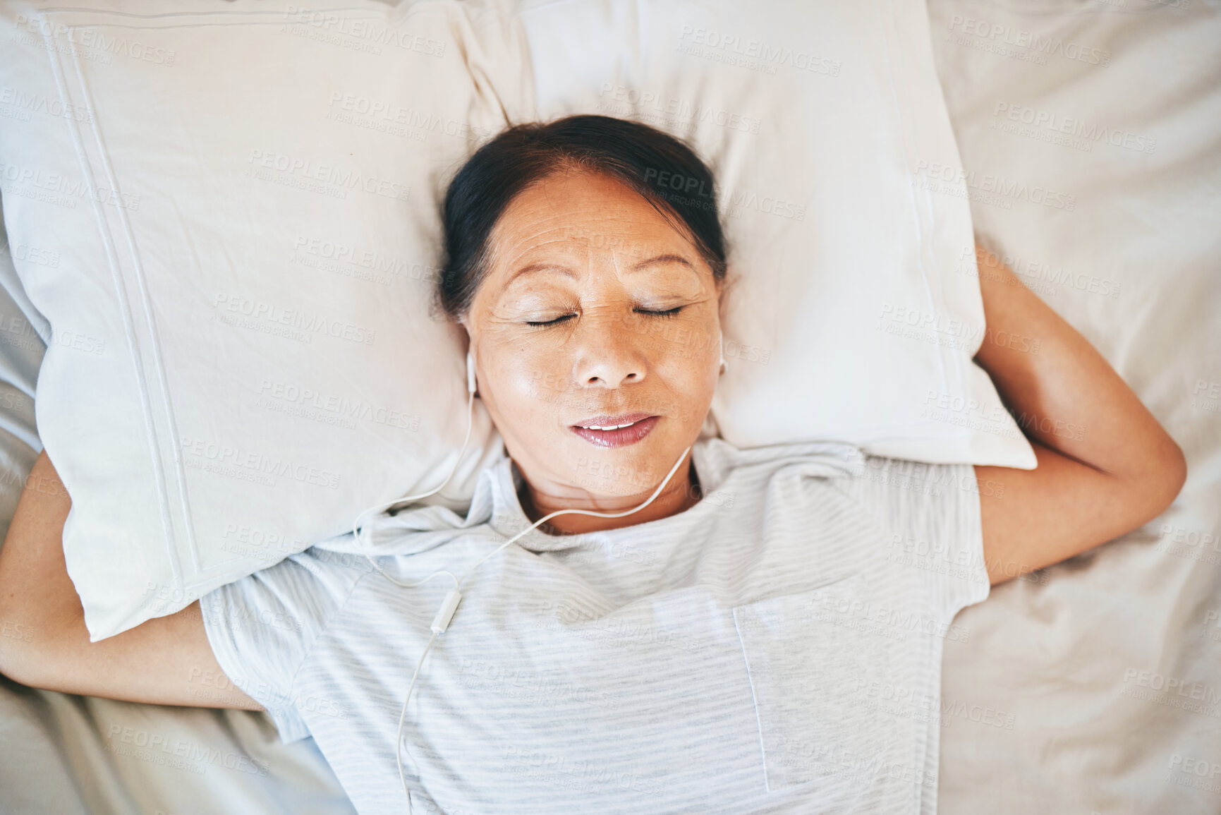 Buy stock photo Bedroom face, music and relax woman sleeping, tired or nap for break, morning wellness or listening to audio podcast. Fatigue, radio sound and top view person cozy, dream and exhausted on home bed
