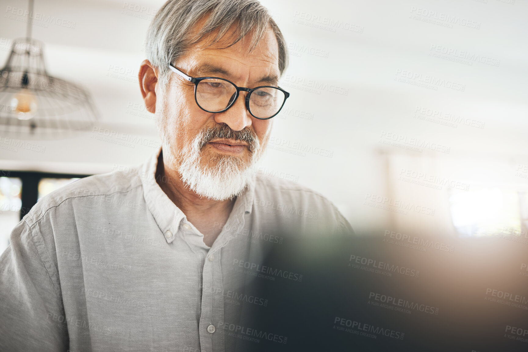 Buy stock photo Laptop, serious and senior man in home on social media, internet search or remote work. Computer, reading and elderly freelancer on website, communication and online on digital technology in house