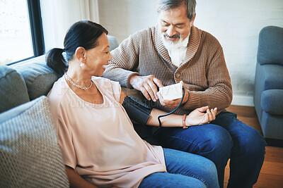 Buy stock photo Blood pressure, healthcare and senior couple in living room with equipment for hypertension. Sick, love and elderly man with medical tool for woman in retirement in the lounge of modern home together