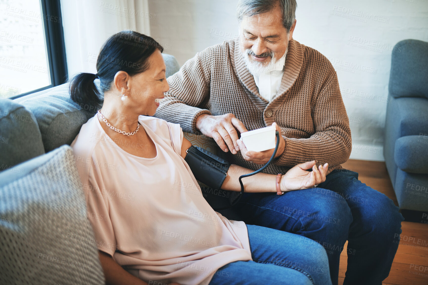 Buy stock photo Blood pressure, healthcare and senior couple in living room with equipment for hypertension. Sick, love and elderly man with medical tool for woman in retirement in the lounge of modern home together