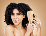 Hair, beauty and confused woman with afro brush for style isolated in a studio brown background for wellness and skincare. Comb, frustrated and angry person with frizzy knots in Brazil hairdresser