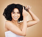 Curly, hair comb and portrait of happy woman in studio for natural beauty, shine or coil texture on brown background. Model, smile and brush afro hairstyle for salon aesthetic, keratin growth or care