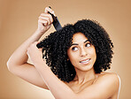 Hair care, afro and woman with a comb, beauty and treatment on a brown background. Person, girl and model with salon grooming, volume or shine with glow, wellness and aesthetic with texture and clean