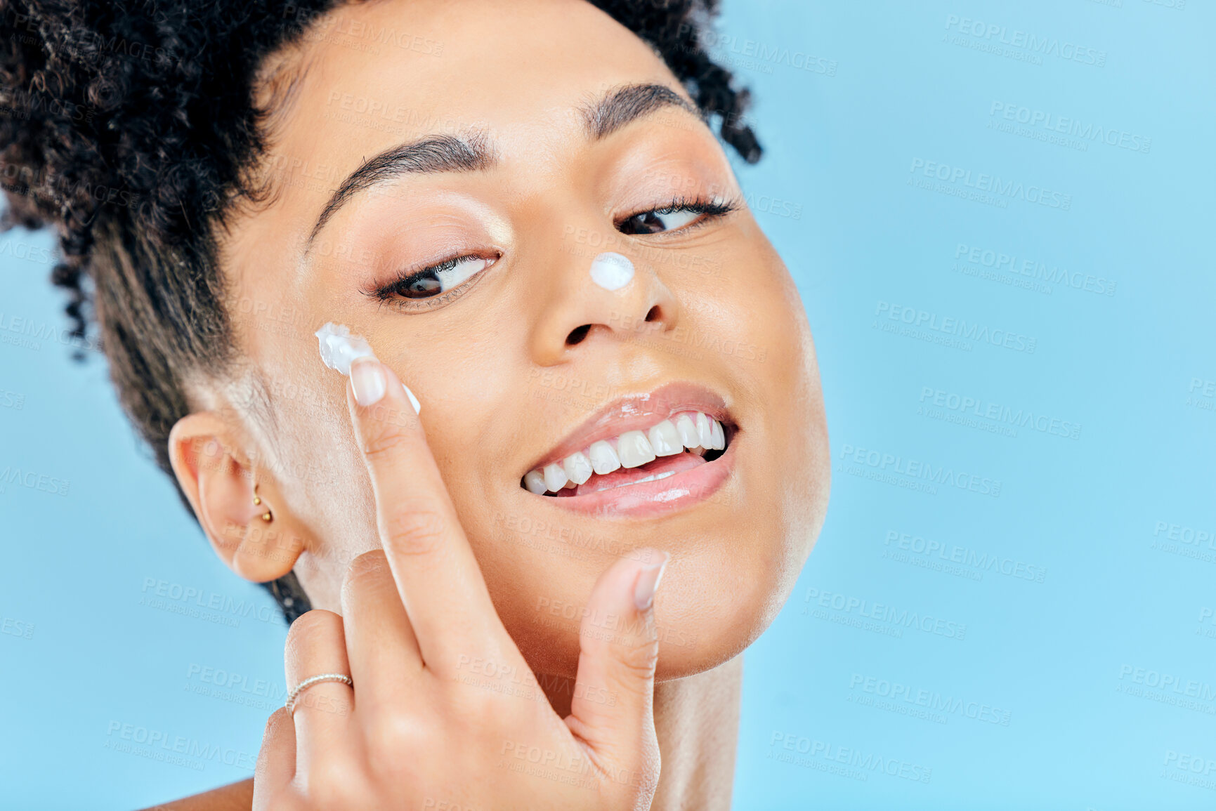 Buy stock photo Happy woman, face and cream for skincare, beauty or cosmetics against a blue studio background. Closeup of female person smile with moisturizer, creme or lotion for spa or facial treatment on mockup