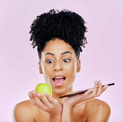 Buy stock photo Woman in studio with apple, chocolate and choice for food, wellness and skincare nutrition. Fruit vs sweets, diet and decision for beauty model on pink background with challenge for healthy eating.