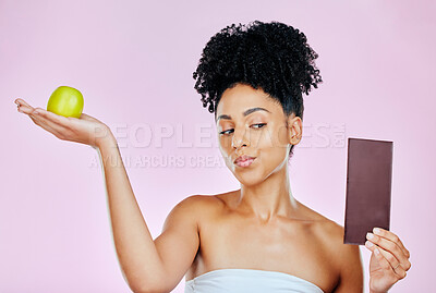 Buy stock photo Woman in studio with apple, chocolate and decision for food, wellness and skincare nutrition. Fruit vs sugar, diet and choice for beauty model on pink background with challenge for healthy eating.