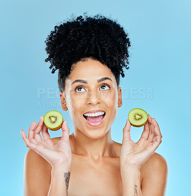 Buy stock photo Kiwi, skincare and excited woman in studio for cosmetic wellness or results on blue background. Happy, face and female with fruit for beauty, pamper or glowing skin routine with detox, shine or glow