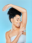 Smile, beauty and underarm deodorant with a woman on a blue background in studio for hygiene. Skincare, product and fresh with a happy young person looking to apply a scent or fragrance to her armpit