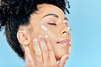 Beauty, face and relax woman with cream application of ointment, lotion or collagen for skin hydration, wellness or spa skincare. Eyes closed, anti aging routine and studio model on blue background
