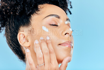 Buy stock photo Beauty, face and relax woman with cream application of ointment, lotion or collagen for skin hydration, wellness or spa skincare. Eyes closed, anti aging routine and studio model on blue background