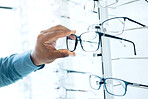 Optometry shop, eyeglasses and hands of person shopping for retail sales decision, optical clinic product or prescription eyewear. Shelf option, ocular accessory and closeup client choice for glasses