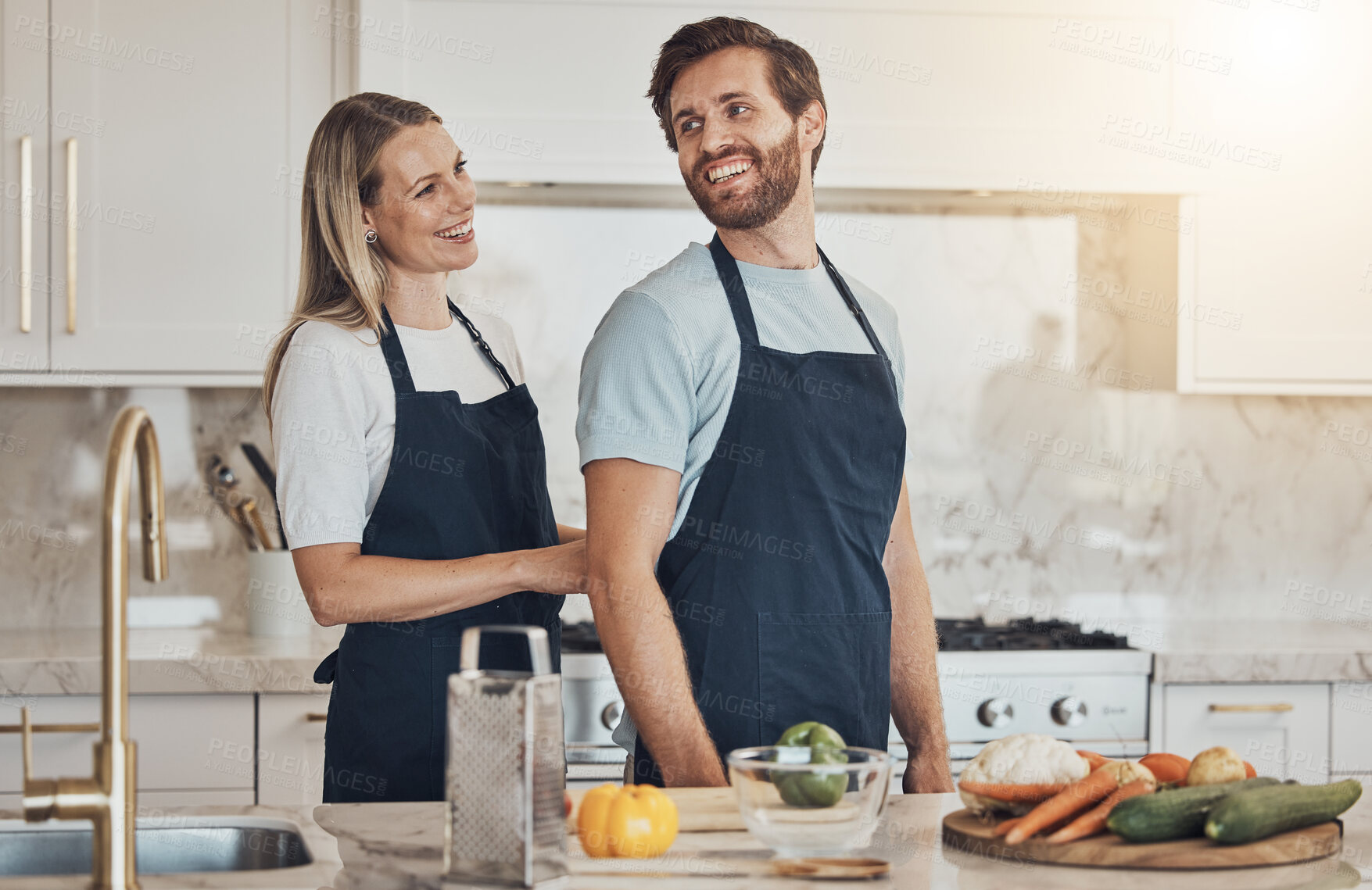 Buy stock photo Kitchen, apron and couple with cooking, smile and healthy food with ingredients, bonding and anniversary. Happy people, home and man with woman, recipe and bonding with activity, lunch and vegetables