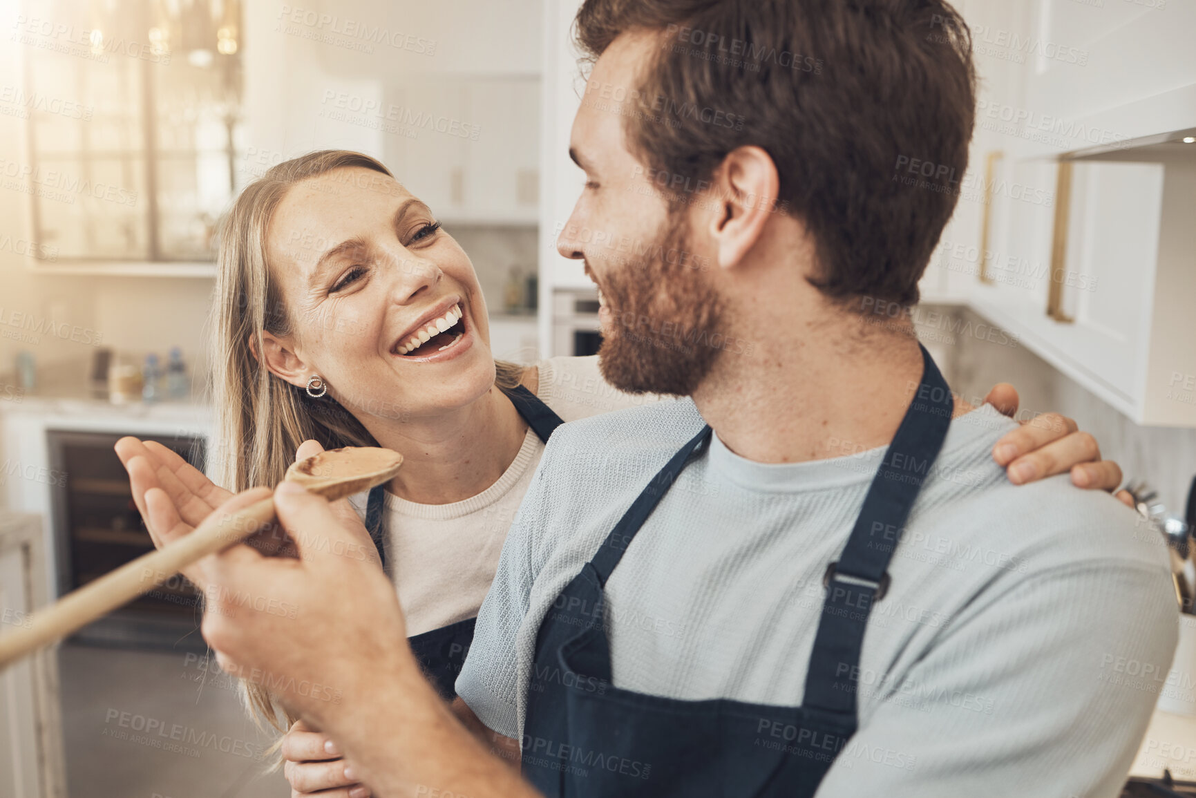 Buy stock photo Cooking, taste and happy couple in kitchen bonding while preparing a meal in their home together. Food, spoon and man feeding woman in a house with romance, smile and having fun on weekend or day off