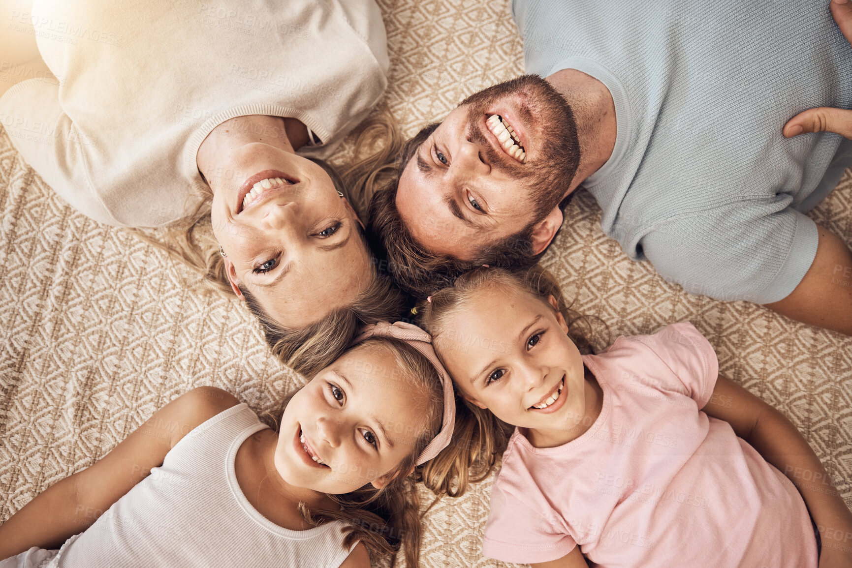 Buy stock photo Love, portrait and top view of happy family on a floor bonding, relax and having fun at home together. Face, smile and children with parents lying in a living room with care, support or security