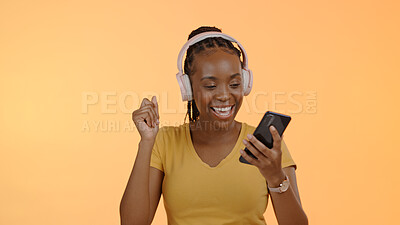 Buy stock photo Woman, music and headset on smartphone to dance, stream podcast or excited by orange background. Happy black person, technology and listen to playlist with online audio, radio and studio mockup