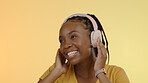 Smile, headphones and black woman with a smartphone, listening and excited on a yellow studio background. African person, model or girl with a headset, joy and cellphone with audio or streaming music