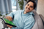Portrait, tablet and green screen with a man gaming on a sofa in the living room of his home to relax. Technology, smile and happy young gamer using a display or screen with tracking markers