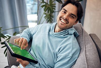 Buy stock photo Portrait, tablet and green screen with a man gaming on a sofa in the living room of his home to relax. Technology, smile and happy young gamer using a display with tracking markers in his apartment