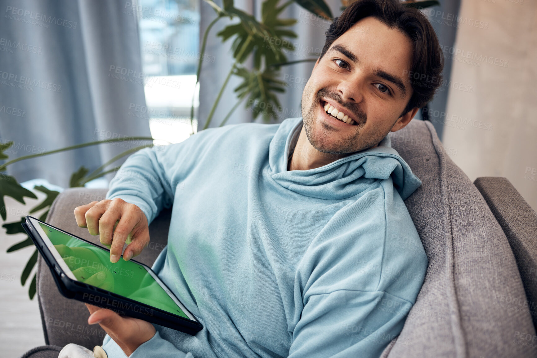 Buy stock photo Portrait, tablet and green screen with a man gaming on a sofa in the living room of his home to relax. Technology, smile and happy young gamer using a display with tracking markers in his apartment