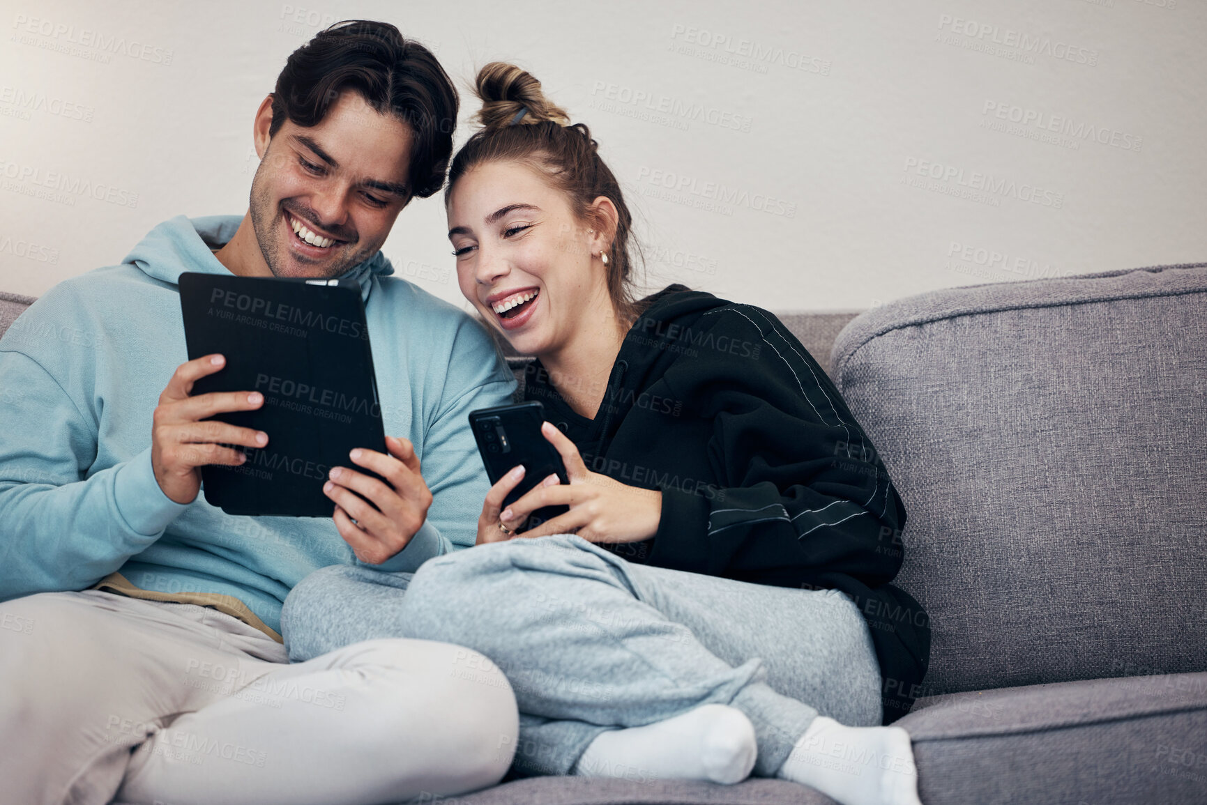 Buy stock photo Couple, phone and tablet with relax on sofa for social media, internet scroll and funny meme with laugh. People, man or woman on couch with smartphone and touchscreen for technology and web streaming