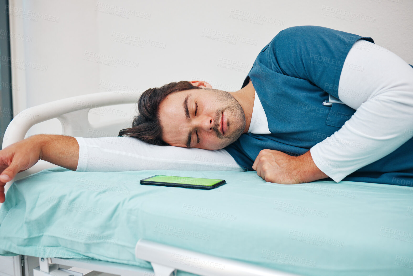 Buy stock photo Sleeping, hospital and tired doctor with phone on bed for rest, nap and break for burnout, exhausted and fatigue. Healthcare, night shift and worker relax for medical service, wellness and stress