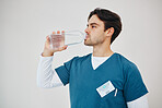 Nurse drink water in bottle for health, wellness or body nutrition in studio isolated on a white background in hospital. Man, medical professional or hydration with liquid of thirsty surgeon on break