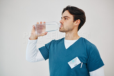 Buy stock photo Nurse drink water in bottle for health, wellness or body nutrition in studio isolated on a white background in hospital. Man, medical professional or hydration with liquid of thirsty surgeon on break