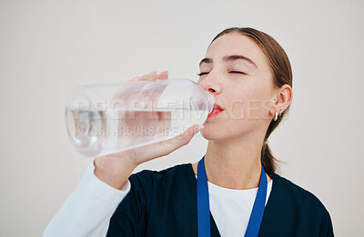 Buy stock photo Nurse, woman drinking water in bottle for health, wellness or body nutrition isolated on white background in hospital. Medical professional, hydration and mineral liquid of thirsty surgeon on a break