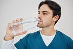 Nurse, man drinking water in bottle and health, wellness or body nutrition in studio isolated on a white background in hospital. Medical professional, hydration and liquid of thirsty surgeon on break