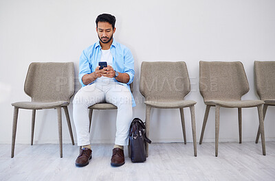 Buy stock photo Waiting room, phone and man in an office for interview in job search for appointment. Hiring, career and Indian male person sitting for recruitment meeting with human resources in modern workplace.