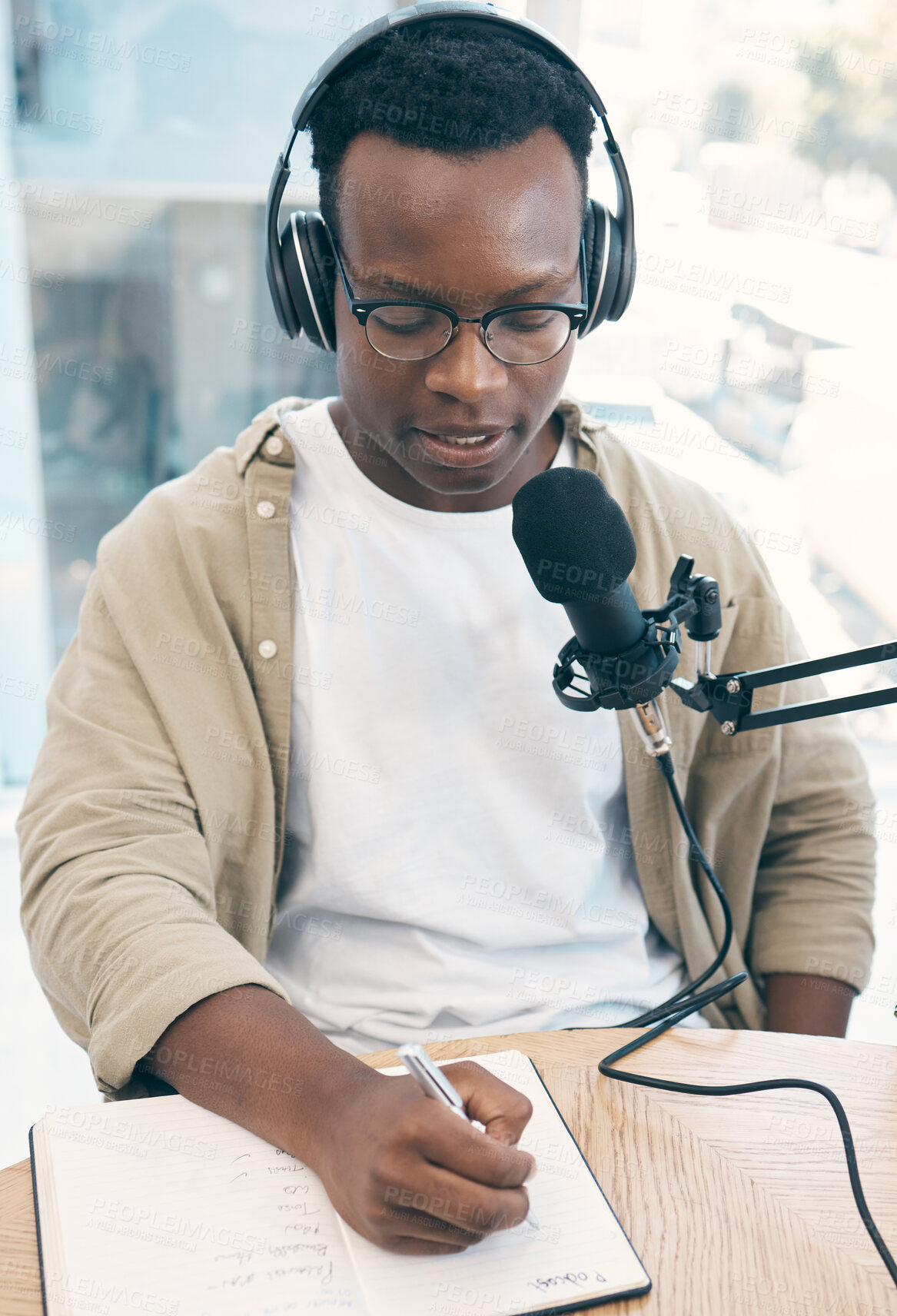 Buy stock photo Radio, podcast and black man in office writing notes for advice, questions or feedback while live streaming. Speech, presenter and African male with broadcast announcement, news or hosting talk show