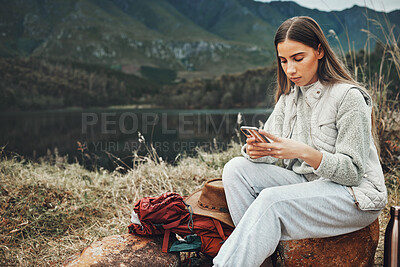 Buy stock photo Nature, phone and young woman hiking on a mountain and network on social media or mobile app. Travel, technology and female person from Canada scroll on internet with cellphone in outdoor forest.