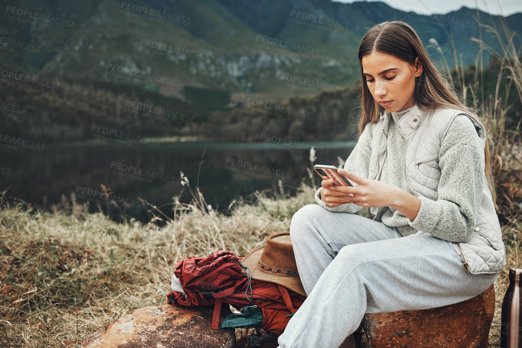 Buy stock photo Nature, phone and young woman hiking on a mountain and network on social media or mobile app. Travel, technology and female person from Canada scroll on internet with cellphone in outdoor forest.