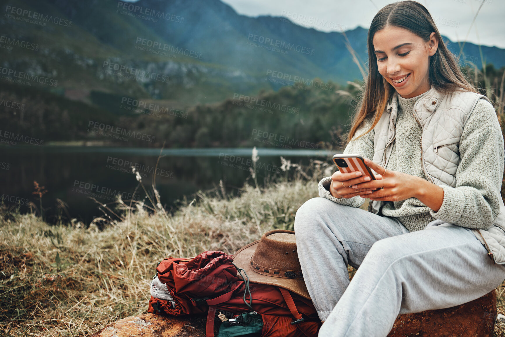 Buy stock photo Nature, smile and woman on a phone for hiking on a mountain and network on social media or mobile app. Happy, technology and young female person scroll on internet with cellphone in outdoor forest.
